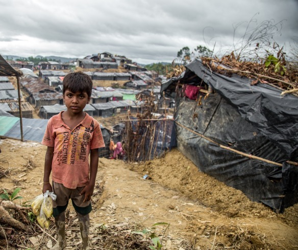 Muk Kashim, aged 8, holds bags of food aid in Cox's Bazar, Bangladesh