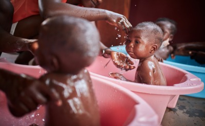 Young children are bathed by their mothers.