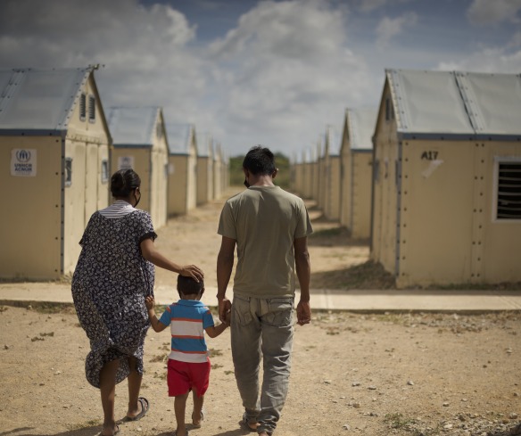 A family displaced by conflict walks through a settlement. Action Against Hunger is supporting families like these with cash transfers to help them buy food, medicine, and other goods.