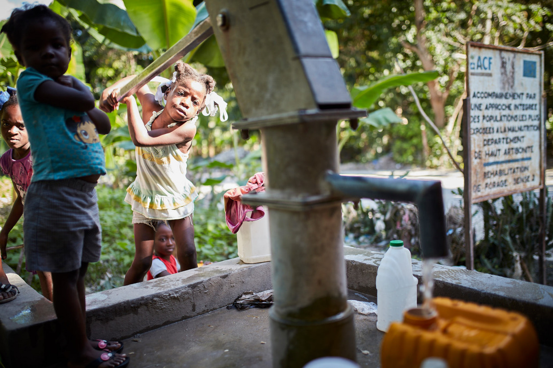 A young girl pumps water from a pump built by Action Against Hunger in 2008. Reliable access to clean water, safe sanitation, and good hygiene remains a challenge in Haiti.