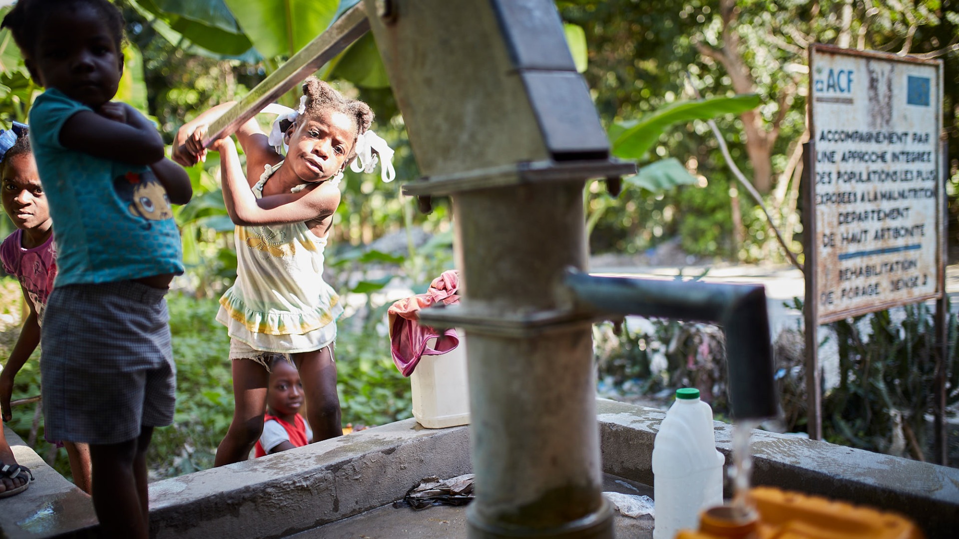 A young girl pumps water from a pump built by Action Against Hunger in 2008. Reliable access to clean water, safe sanitation, and good hygiene remains a challenge in Haiti.