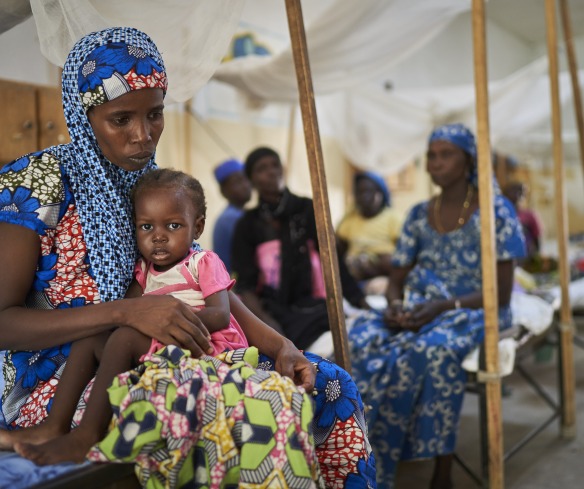 A mother sits with her daughter on her lap in an Action Against Hunger Nutrition Center.