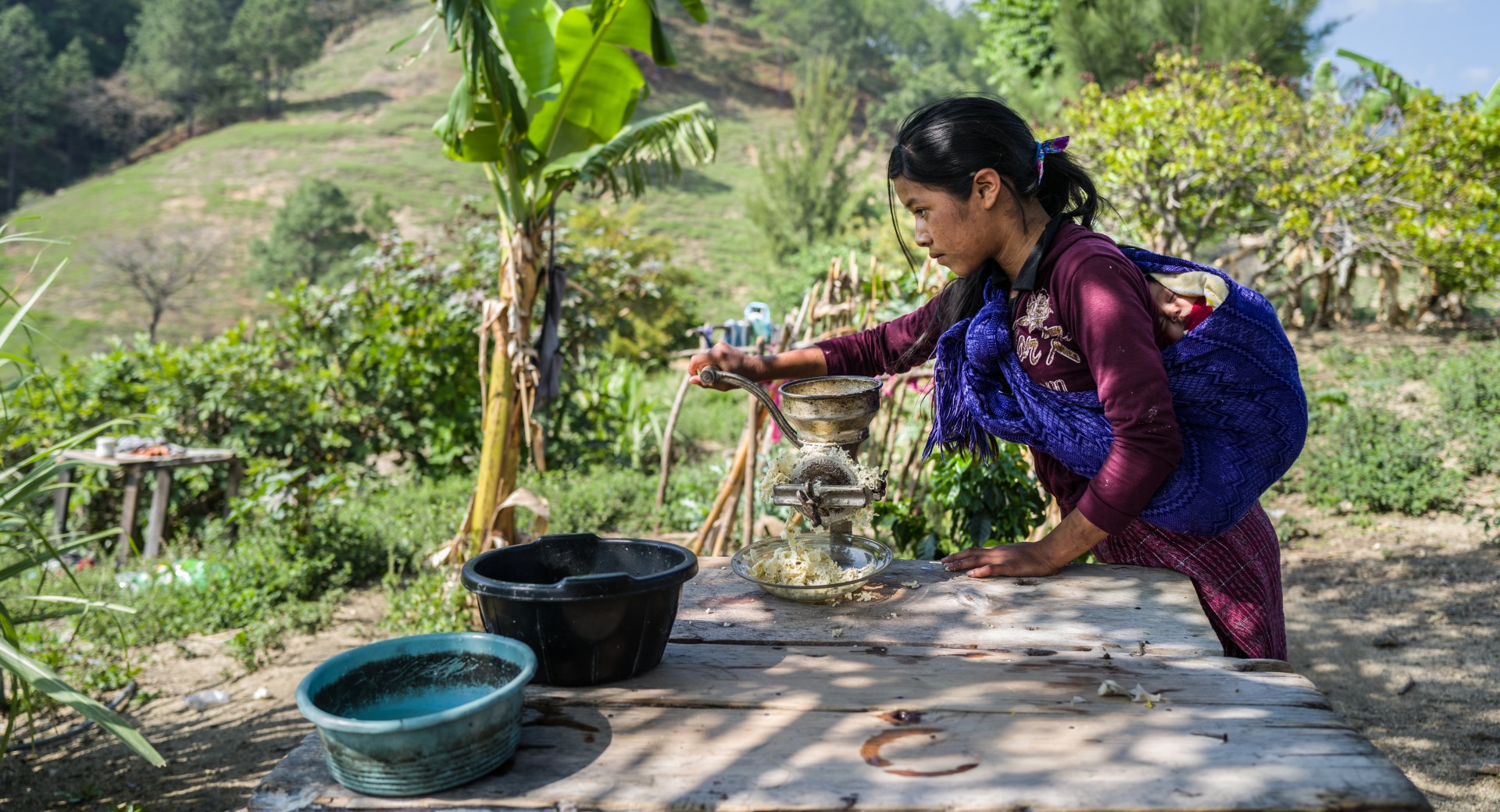 A girl grinds a crop grown in her community.