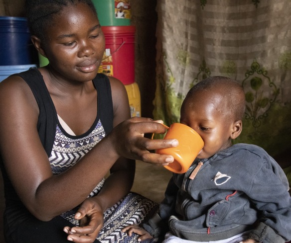 Mariam feeds her son Goodluck a milk formula to help him recover from malnutrition