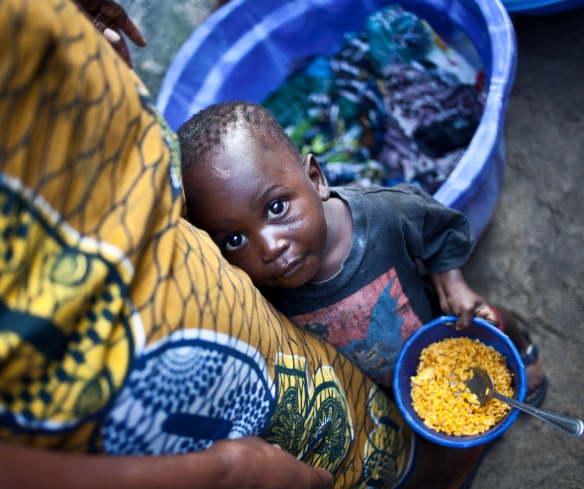 A child eats rice standing next to his mother in Monrovia, Liberia.