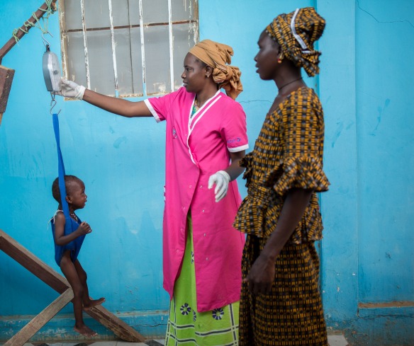 A health worker weighs a child to determine his nutrition status.