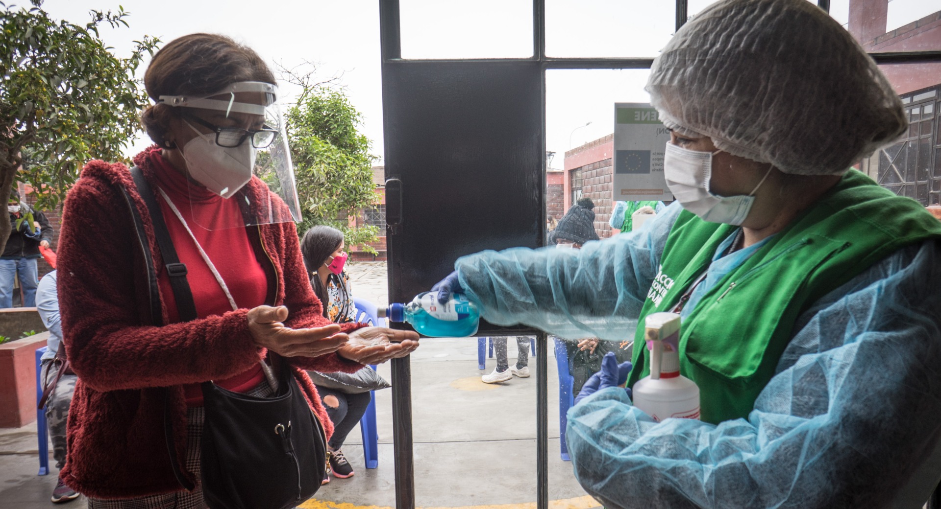 Action Against Hunger's teams in Lima, Peru, provide hand sanitizer for those waiting in line to receive hygiene kits.