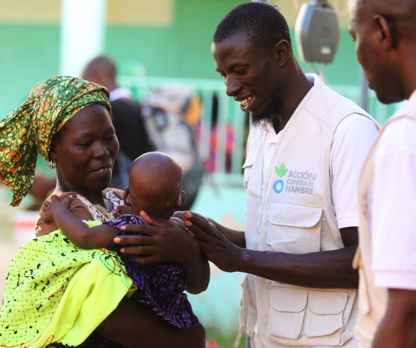 Two Action Against Hunger aid workers check in with a mother and child.