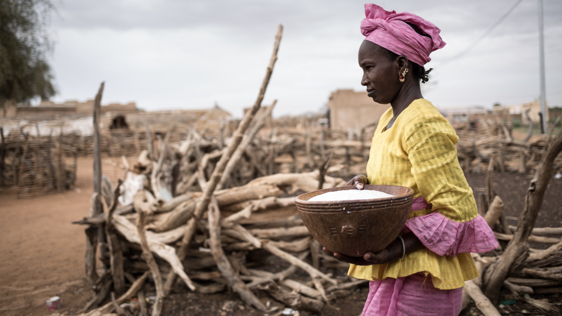 A woman carries a bowl of rice.