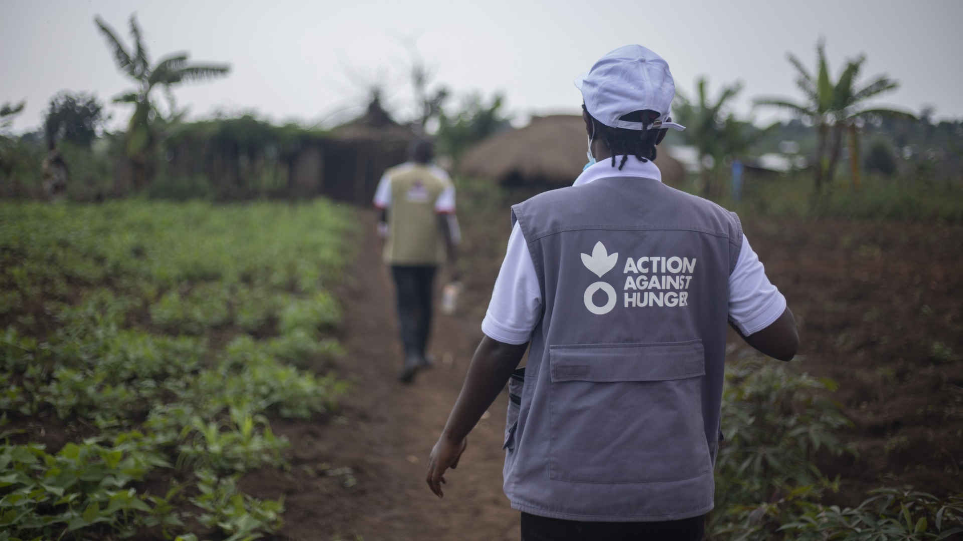 An Action Against Hunger aid worker walks through a field.