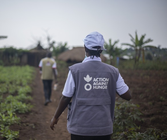 An Action Against Hunger aid worker walks through a field.