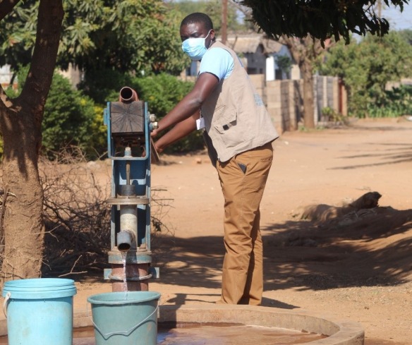 An Action Against Hunger aid worker gets water from a pump.