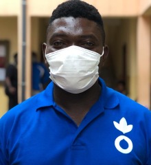 An Action Against Hunger aid worker in a mask looks at the camera.