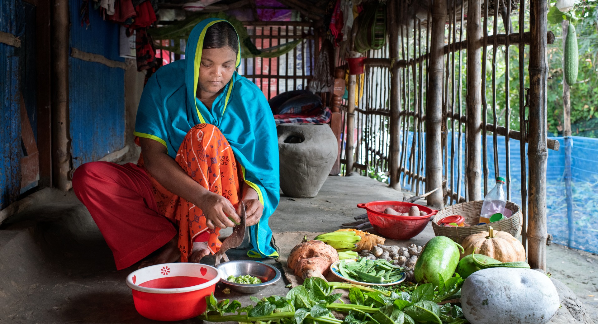 Une femme prépare des légumes et des fruits pour un repas familial.