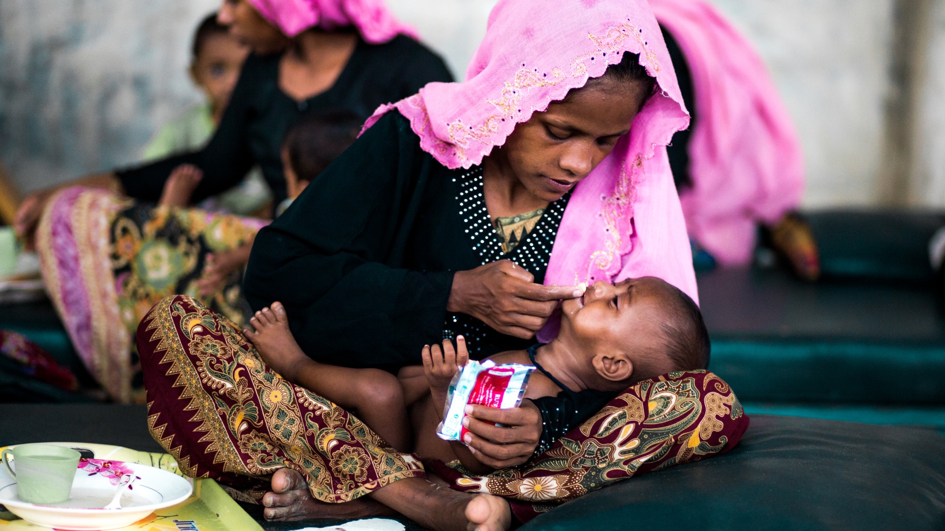 A mother gives her baby Plumpy'Nut to treat malnutrition at an Action Against Hunger nutrition center.