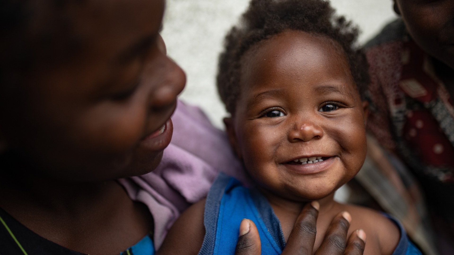 A girl holds her smiling little sister.