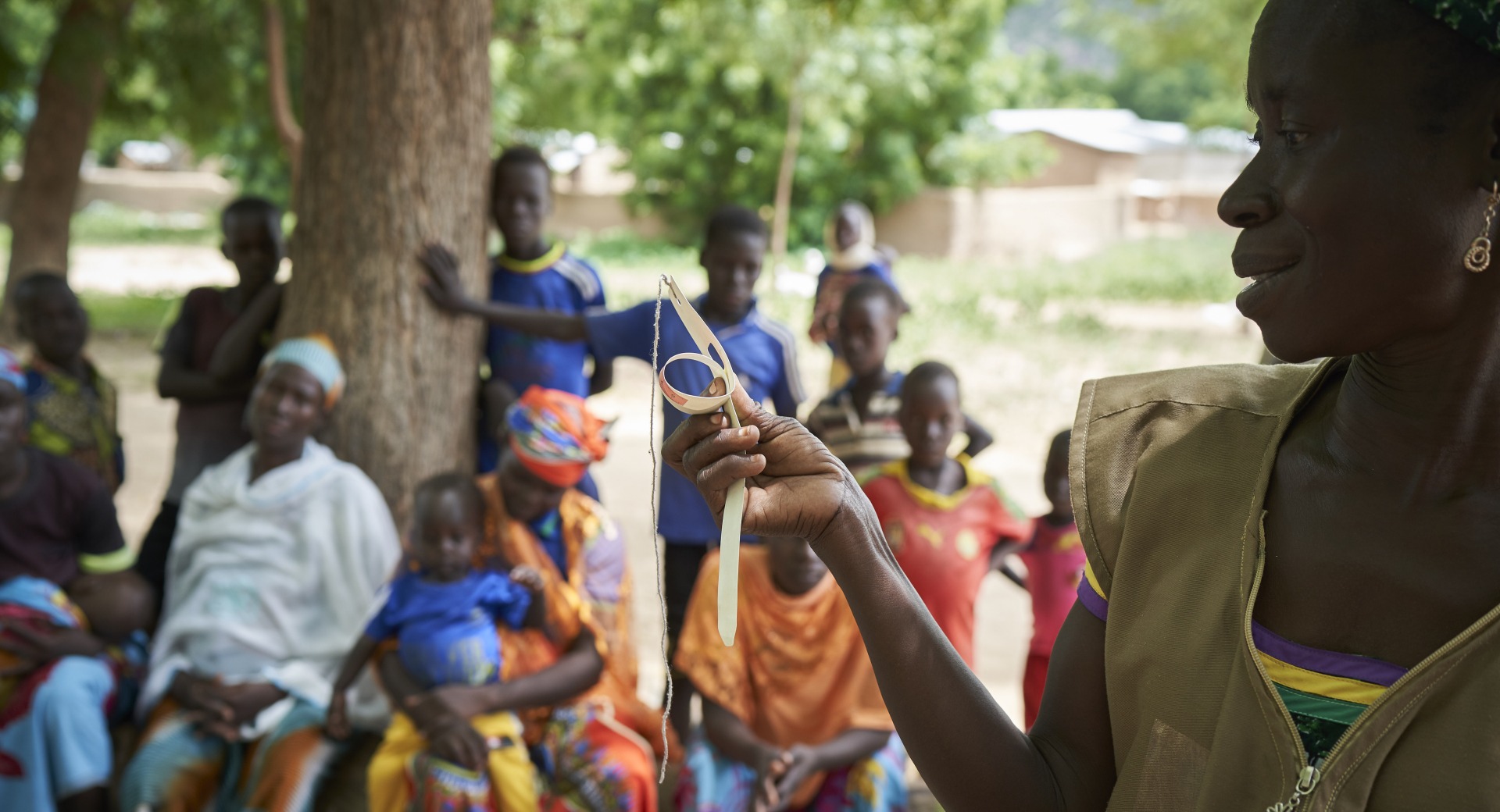 At a community training, a member of our team trains parents how to use a color-coded measuring band to check their children's nutrition status.