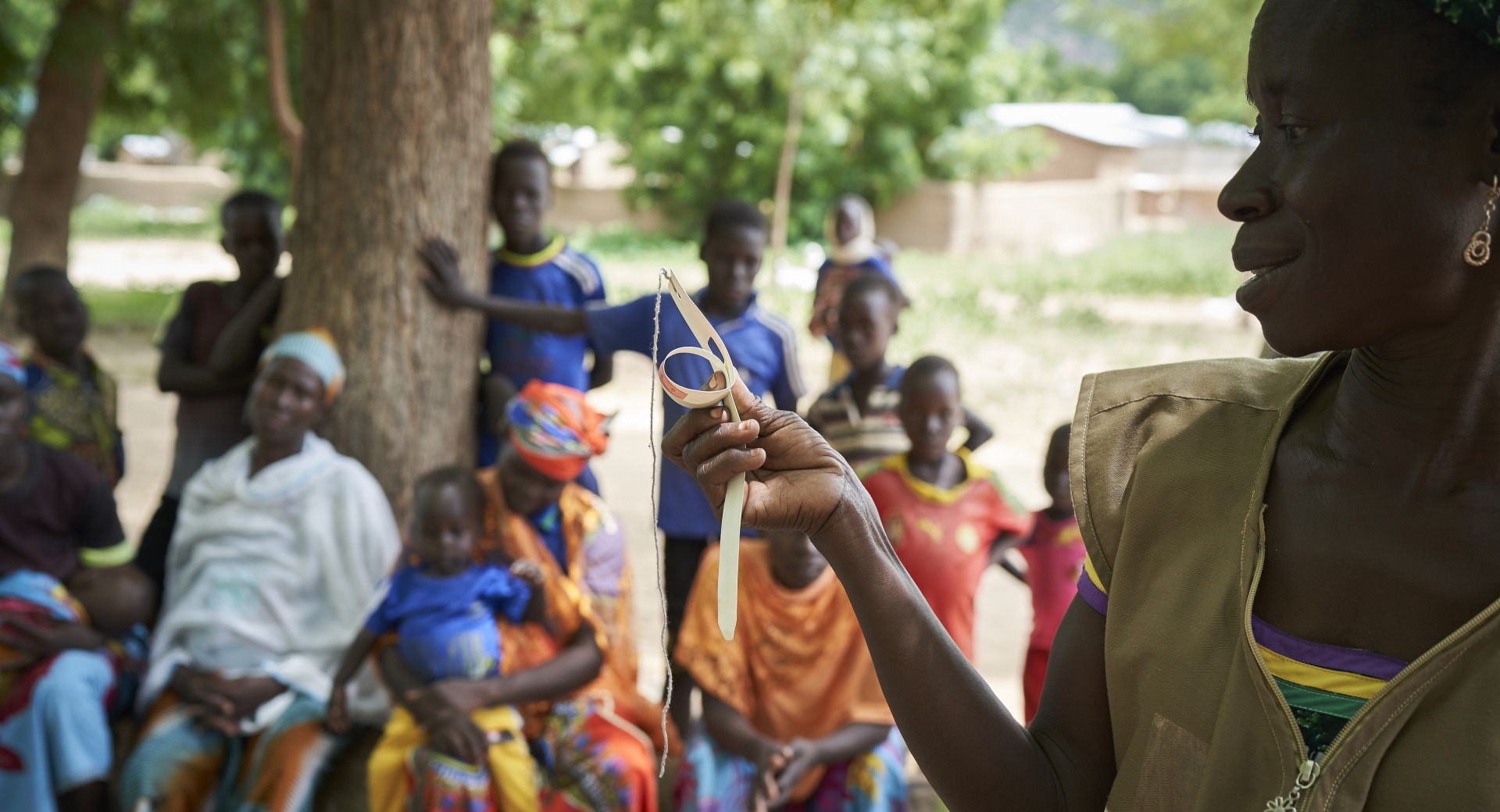 At a community training, a member of our team trains parents how to use a color-coded measuring band to check their children's nutrition status.