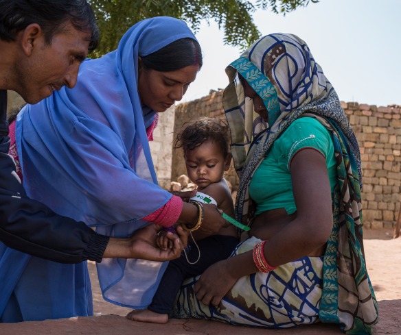 A community health worker shows a mother how to measure her child's nutrition status.