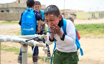 A boy splashes water on his face at a tap installed by Action Against Hunger.