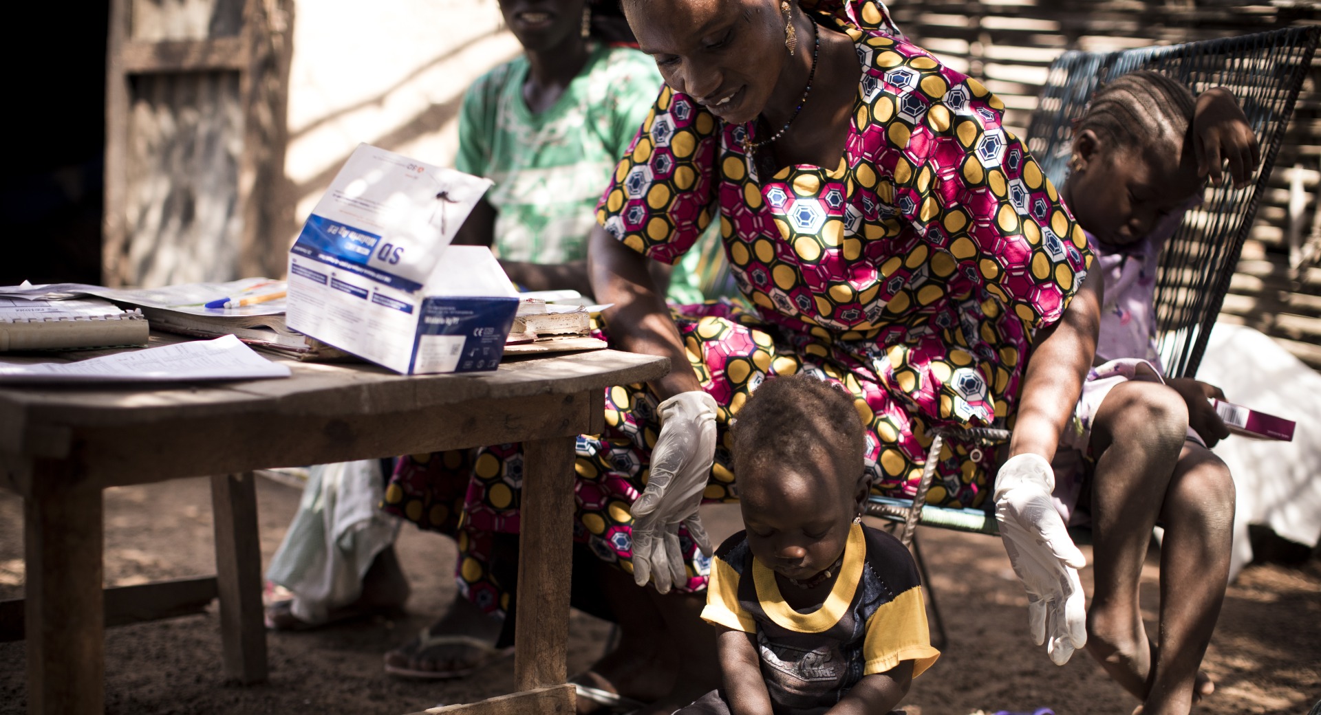 Hawa, an Action Against Hunger-trained community health worker, weighs a child as a part of a routine health check up.