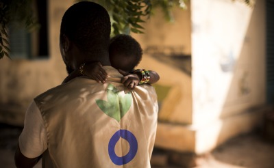 An Action Against Hunger Aid Worker holds a child in his arms in Mali.