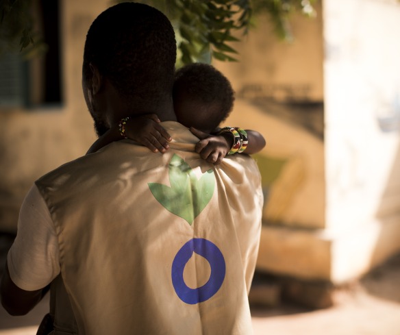 An Action Against Hunger Aid Worker holds a child in his arms in Mali.