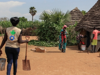 Un travailleur d&#039;Action contre la faim apporte du matériel de creusement à une mère qui souhaite construire des latrines chez elle pour protéger la santé de sa famille.