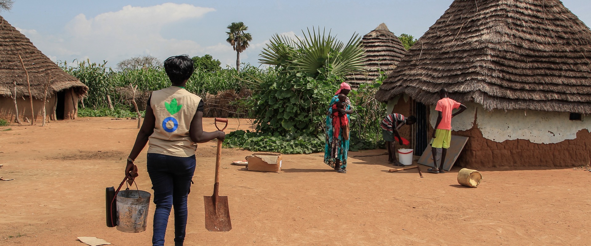 An Action Against Hunger worker brings digging supplies to a mother, who wants to build a latrine at home to help protect her family's health.