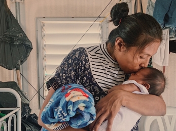 A mother kisses her baby. Her family was displaced by conflict and now receives cash support from Action Against Hunger.