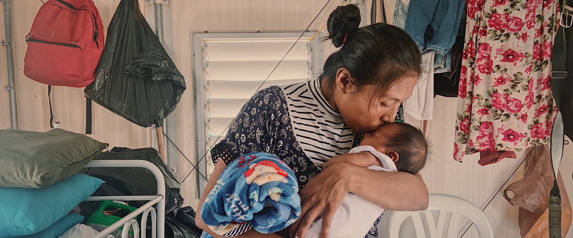 A mother kisses her baby. Her family was displaced by conflict and now receives cash support from Action Against Hunger.
